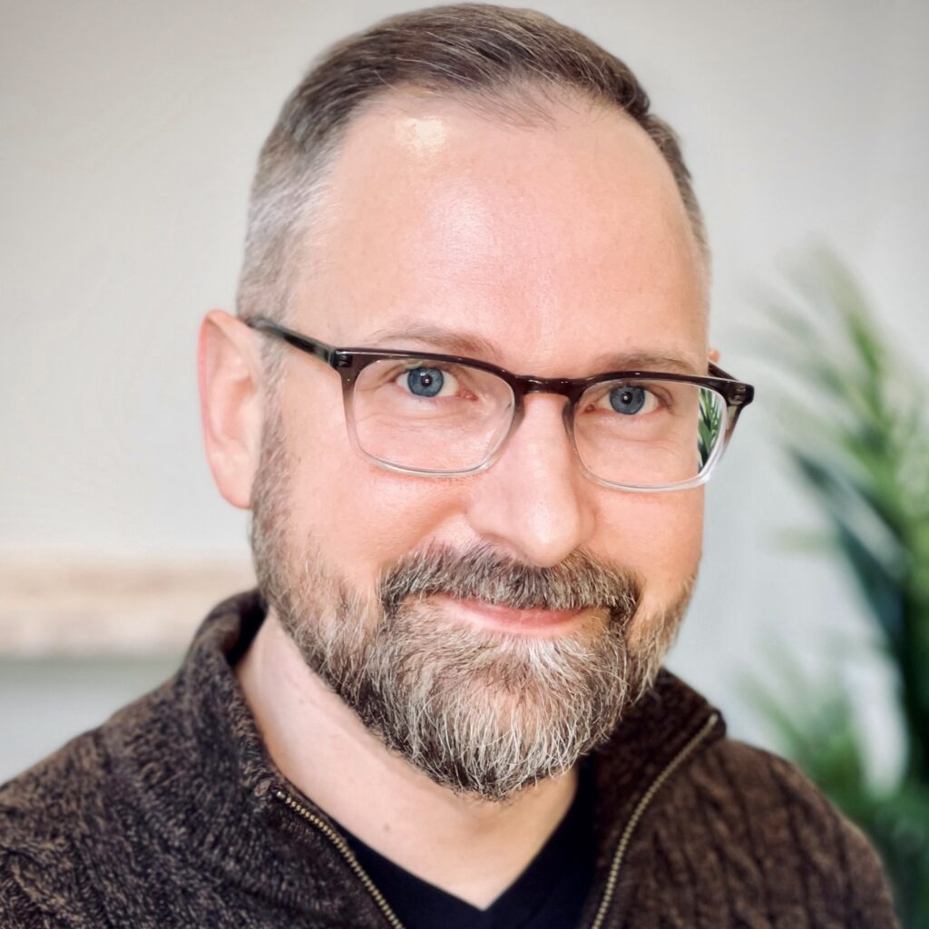 photo of Keith Dow, middle aged man with glasses and a beard in a brown sweater, smiling