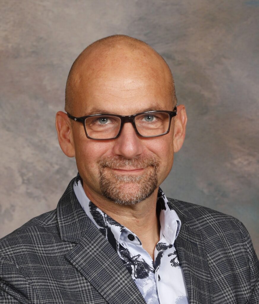 profile photo of John with a glasses, a blazer, and short goatee